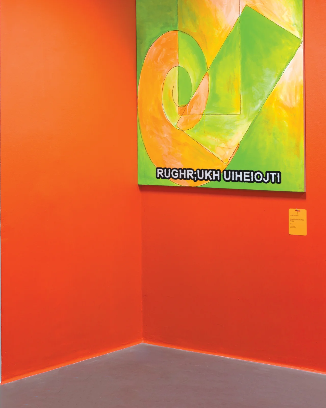 Intensywnie pomarańczowy narożnik galerii z zielono-żółtym obrazem abstrakcyjnym z motywem spirali i zagadkowym tekstem na dole.