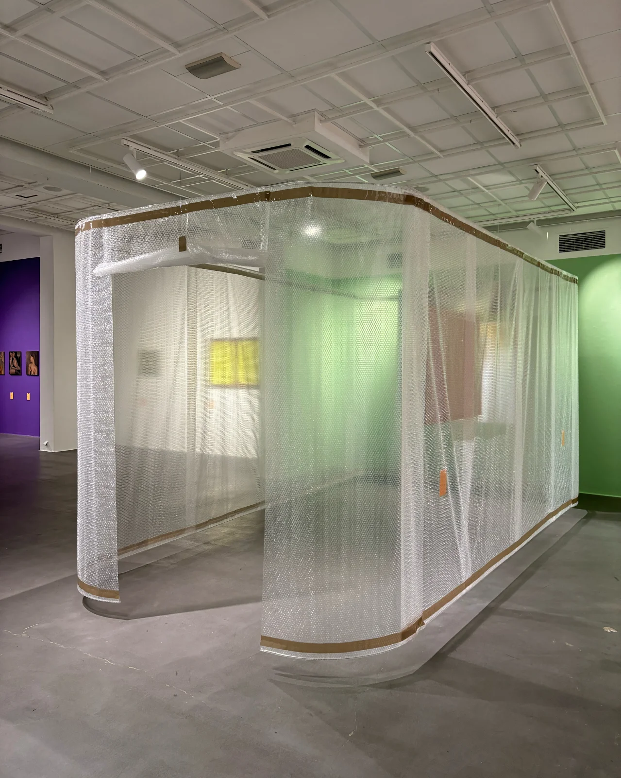 Duża, prostopadłościenna instalacja – kaplica – wykonana z przemysłowej folii bąbelkowej, stojąca w centrum przestrzeni galerii.