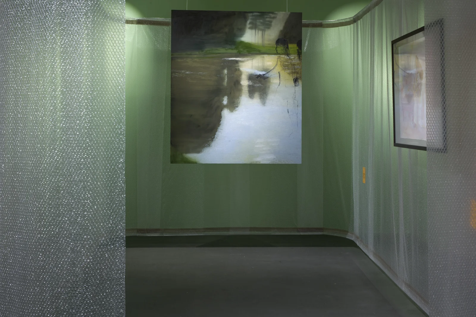 Widok kaplicy w przyciemnionym świetle; obraz przedstawiający odbicie w wodzie zawieszony za półprzezroczystym ekranem z folii bąbelkowej.