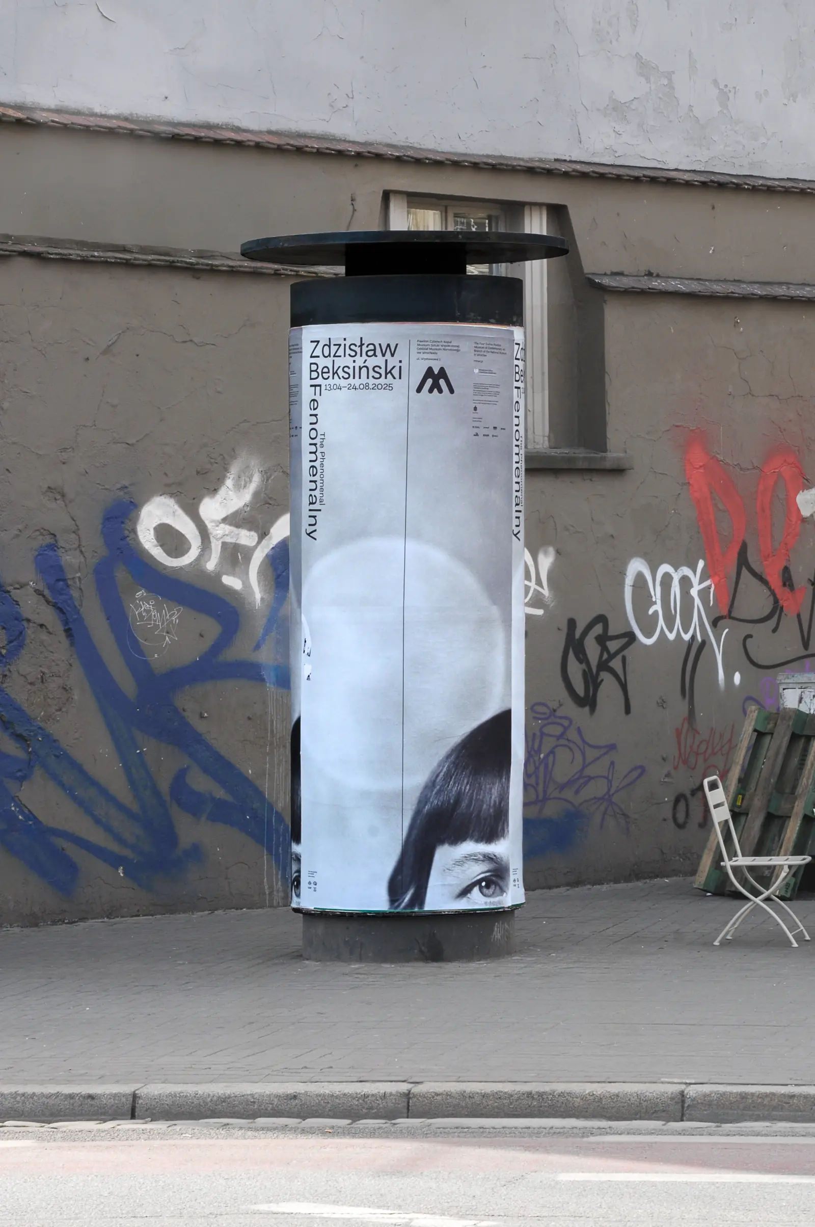 Plakat wystawy „Fenomenalny. Zdzisław Beksiński” na słupie plakatowym na ulicy Wrocławia.