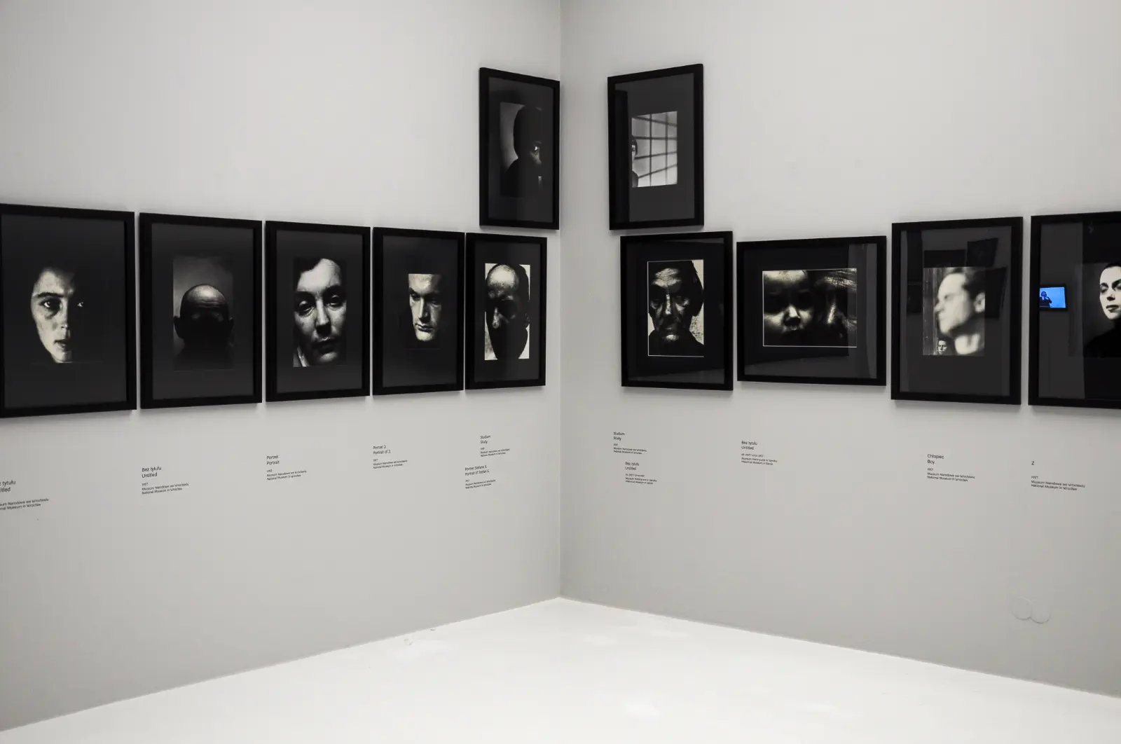 Fenomenalny. Zdzisław Beksiński”. Rząd czarno-białych fotografii portretowych w czarnych ramach.