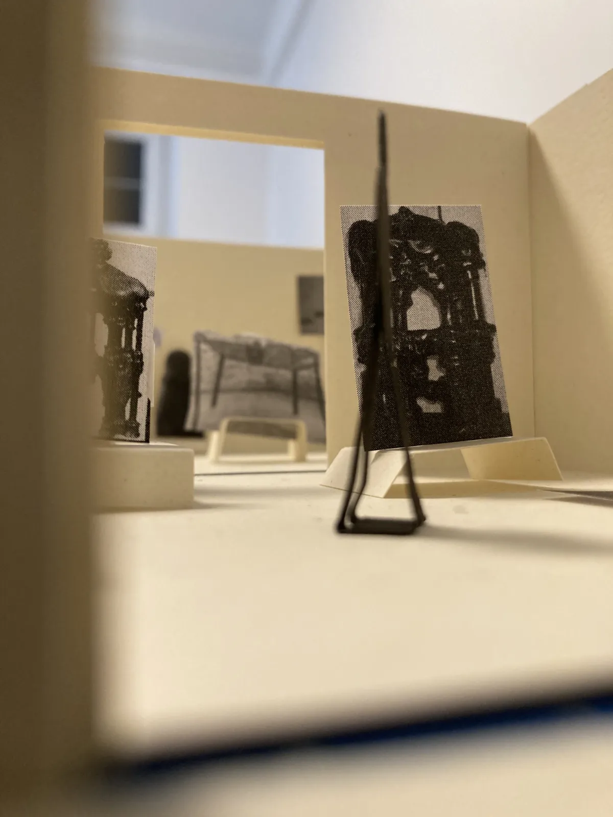 Widok wnętrza makiety wykonany z niskiej perspektywy. W miniaturowych salach widać reprodukcje dzieł sztuki na postumentach i ścianach, co oddaje planowaną aranżację przestrzeni.