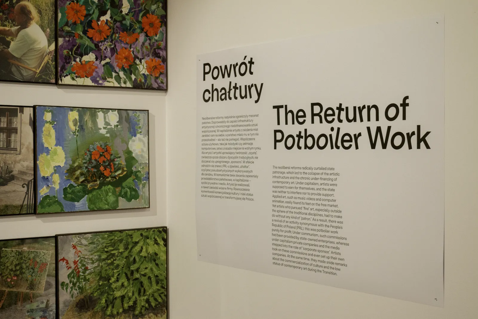 Zbliżenie na planszę z tekstem „Powrót chałtury”. Po lewej stronie widoczne fragmenty kolorowych obrazów z motywami kwiatowymi.