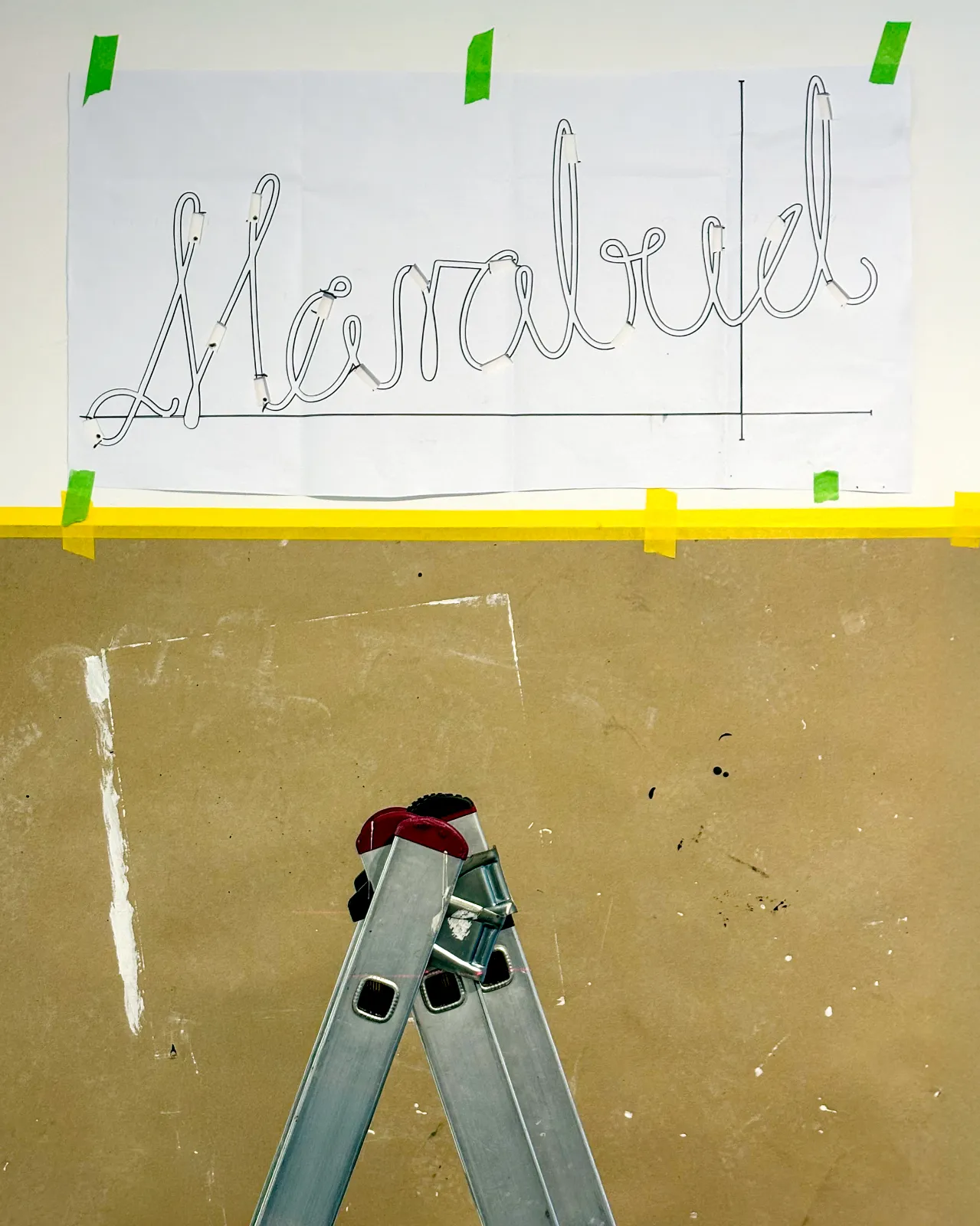 Papierowy szablon neonu „Marabud” przyklejony taśmą do ściany podczas montażu wystawy.