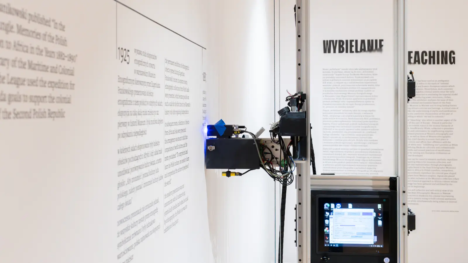 Mobilna drukarna w sali ekspozycyjnej, nanosi na ścianę oś czasu pokazywaną na wystawie.