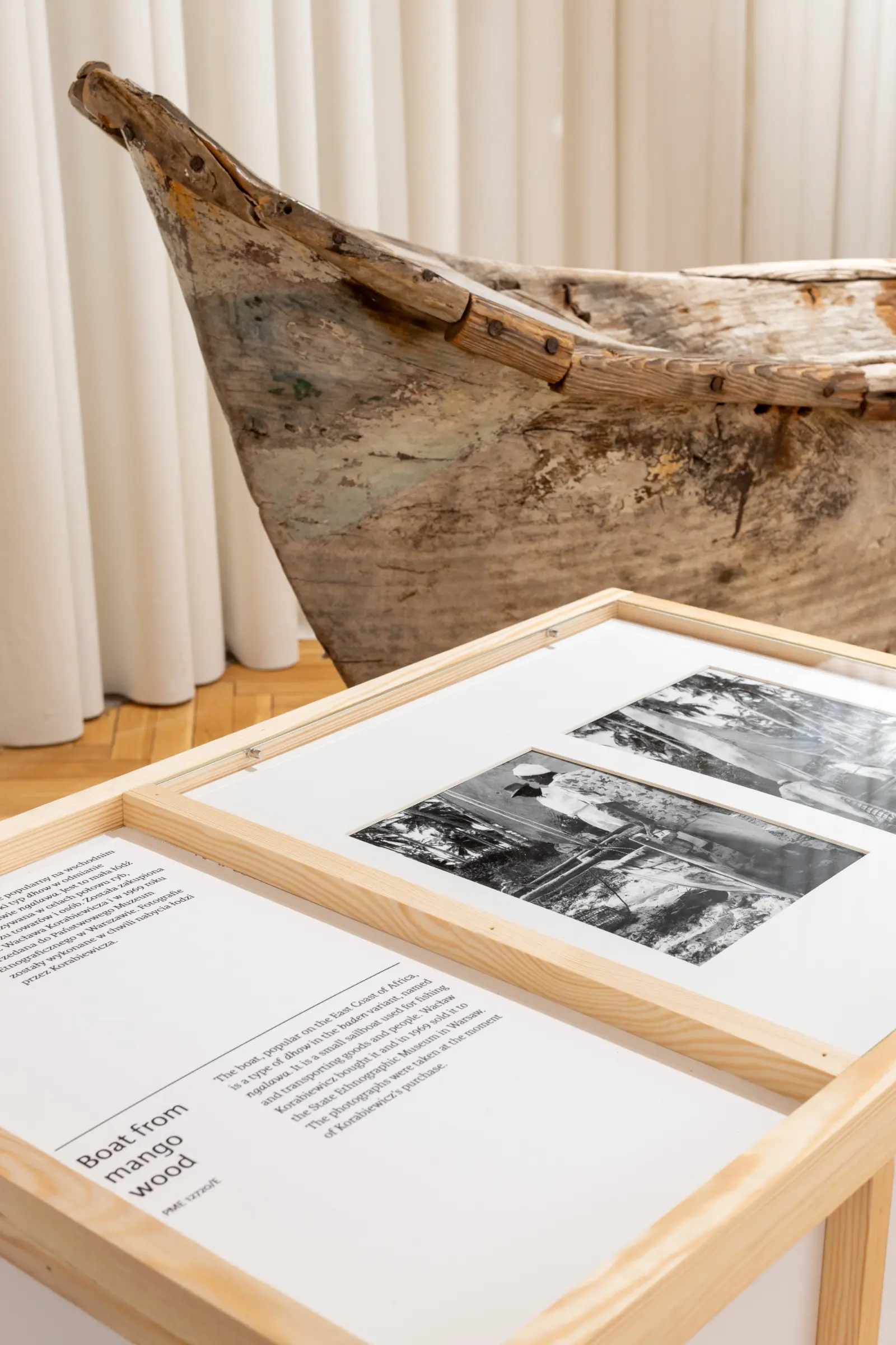 Widok wystawy. Na pierwszym planie gabloty z artefaktami. Dalej fragment starej łodzi.