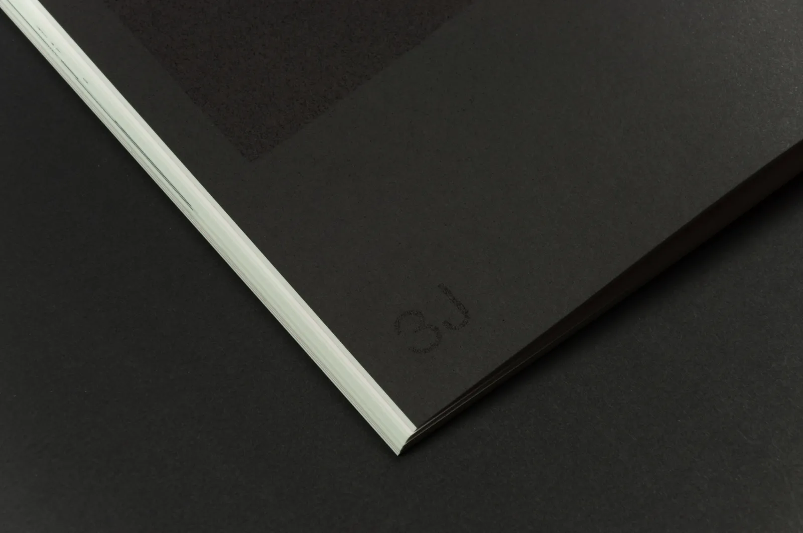 Zbliżenie na fragment książki z prawie czarnym tłem i jeszcze ciemniejszym elementem typograficznym