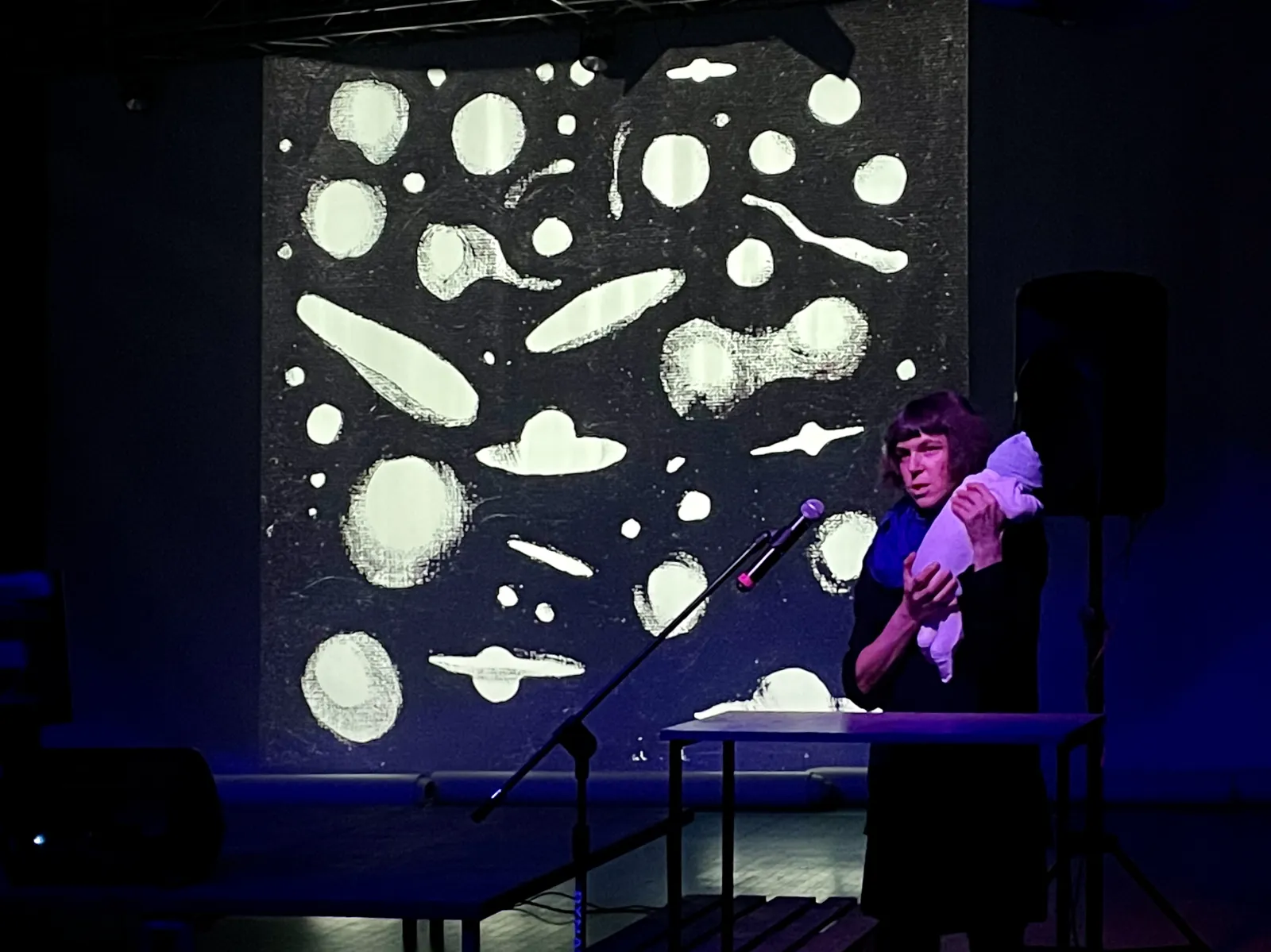 Gościni występuje na scenie, w tle widoczny symbol kosmosu