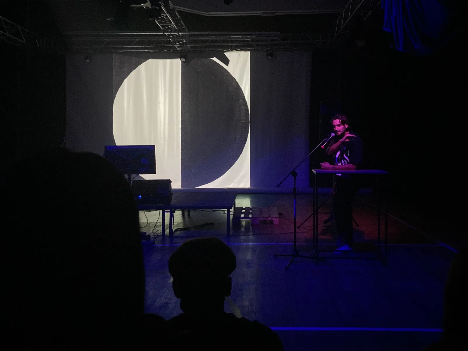 Gość występuje na scenie, w tle widoczny jeden z symboli